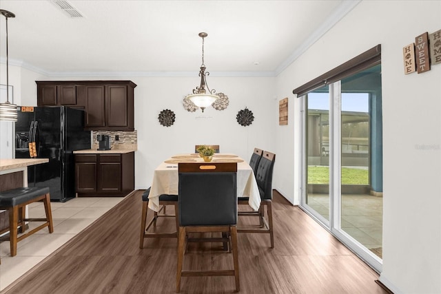 dining space featuring ornamental molding and light wood-type flooring