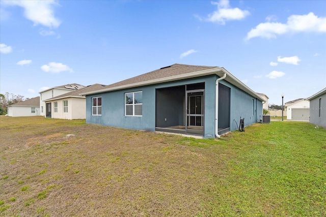 rear view of property with a sunroom, cooling unit, and a lawn