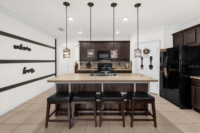 kitchen featuring pendant lighting, sink, a kitchen island with sink, dark brown cabinets, and black appliances