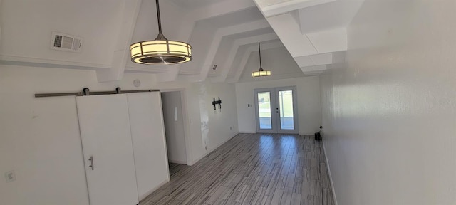 foyer with french doors, a barn door, light hardwood / wood-style floors, and lofted ceiling with beams