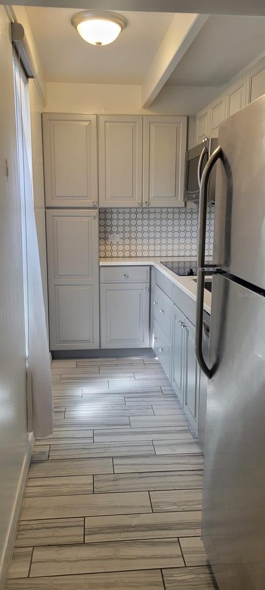 kitchen with appliances with stainless steel finishes and beam ceiling