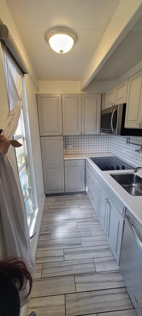 kitchen with gray cabinets, sink, dishwashing machine, decorative backsplash, and black electric cooktop