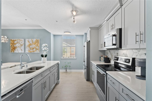 kitchen featuring gray cabinets, sink, decorative backsplash, light hardwood / wood-style floors, and stainless steel appliances