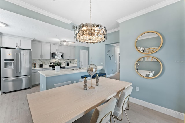 dining space featuring crown molding, sink, a notable chandelier, and light hardwood / wood-style floors