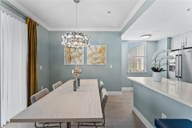 dining space with ornamental molding, a textured ceiling, a notable chandelier, and light hardwood / wood-style floors