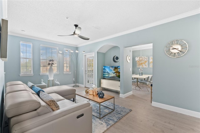 living room with ceiling fan, crown molding, light hardwood / wood-style floors, and a textured ceiling