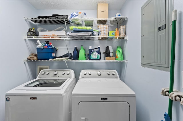 washroom with a textured ceiling, electric panel, and independent washer and dryer