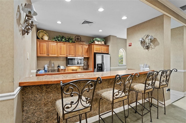 kitchen with appliances with stainless steel finishes, a kitchen breakfast bar, and kitchen peninsula