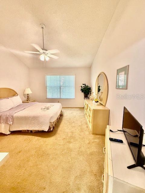 carpeted bedroom featuring ceiling fan and a textured ceiling