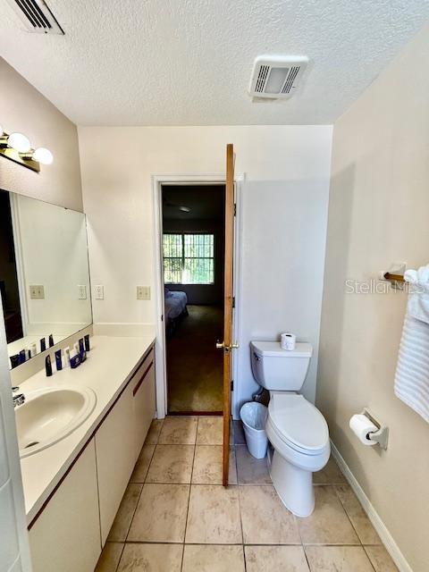 bathroom with tile patterned flooring, vanity, a textured ceiling, and toilet