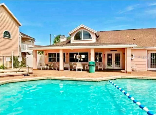 rear view of house featuring a fenced in pool, a patio area, and french doors