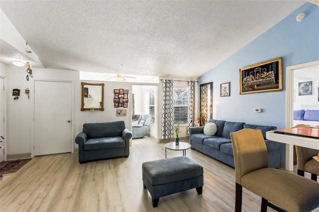 living room featuring ceiling fan, lofted ceiling, light hardwood / wood-style flooring, and a textured ceiling