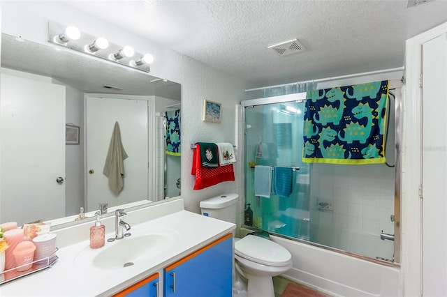 full bathroom with bath / shower combo with glass door, vanity, a textured ceiling, and toilet