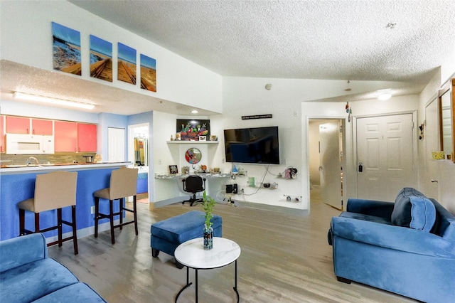 living room with hardwood / wood-style flooring, lofted ceiling, and a textured ceiling