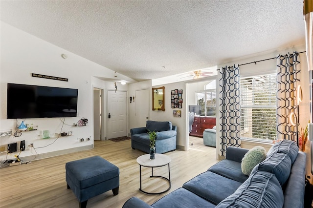 living room with vaulted ceiling, ceiling fan, a textured ceiling, and light wood-type flooring