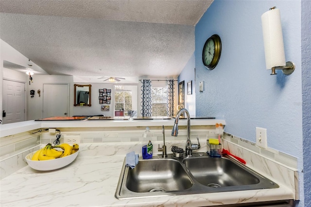 kitchen with sink, a textured ceiling, and ceiling fan