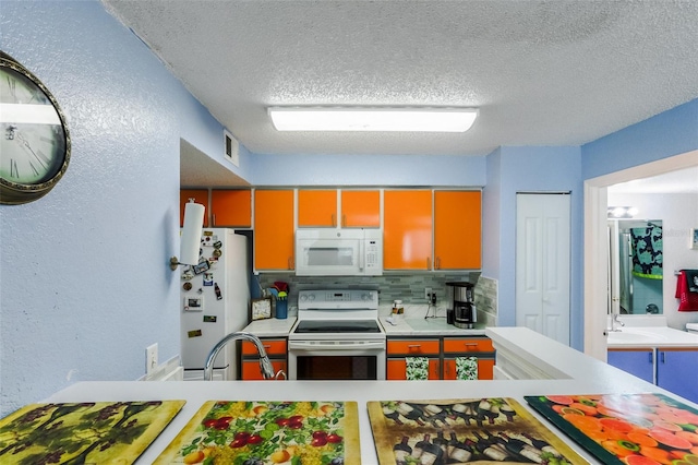 kitchen featuring tasteful backsplash, sink, white appliances, and a textured ceiling