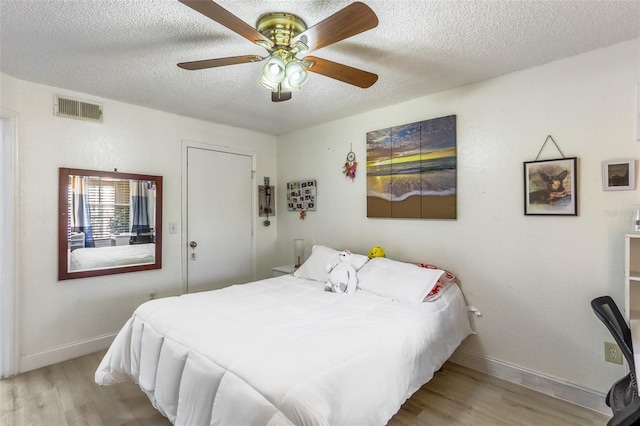 bedroom featuring ceiling fan, a textured ceiling, and light wood-type flooring