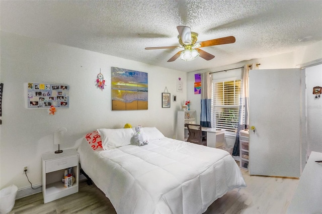 bedroom with ceiling fan, light hardwood / wood-style flooring, and a textured ceiling