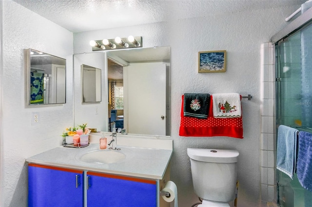 bathroom with vanity, toilet, a shower with shower door, and a textured ceiling