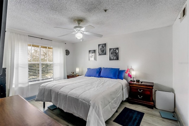 bedroom with ceiling fan, a textured ceiling, and light wood-type flooring