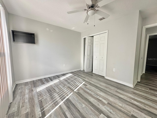 unfurnished bedroom with hardwood / wood-style flooring, ceiling fan, a textured ceiling, and a closet