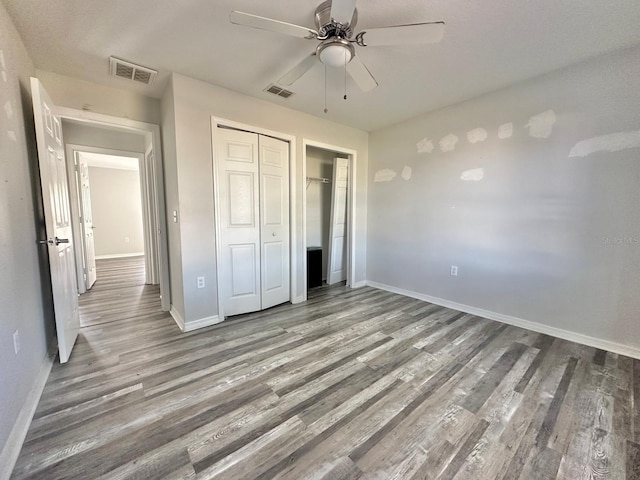 unfurnished bedroom with ceiling fan, wood-type flooring, and a closet