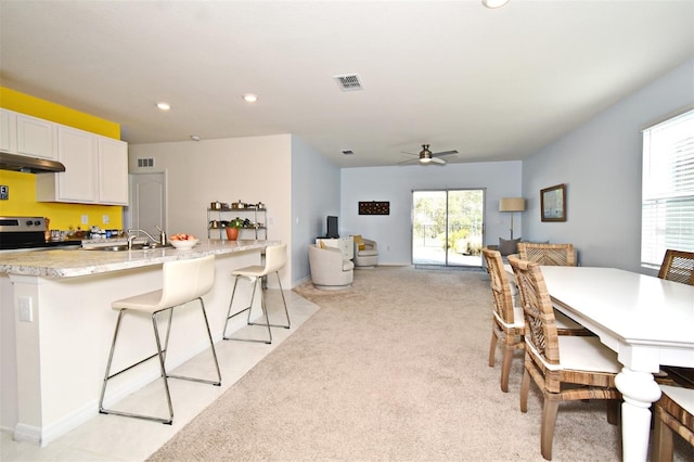 carpeted dining area with sink, a wealth of natural light, and ceiling fan