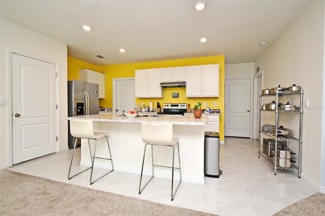 kitchen featuring white cabinetry, stainless steel appliances, a breakfast bar, and a kitchen island with sink