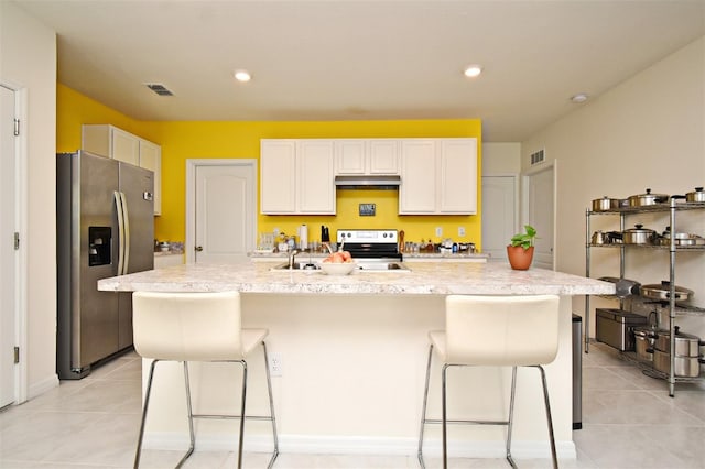 kitchen featuring a kitchen island with sink, light tile patterned floors, white cabinetry, and stainless steel appliances