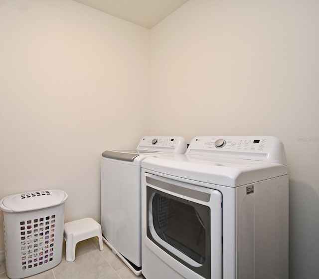 clothes washing area with light tile patterned floors and washer and dryer