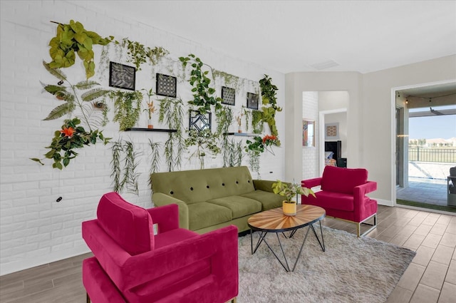 living room featuring brick wall and wood-type flooring