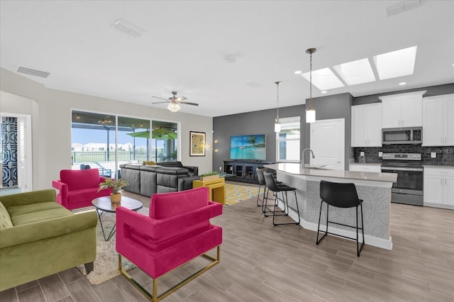 living room featuring a healthy amount of sunlight, sink, and light hardwood / wood-style flooring