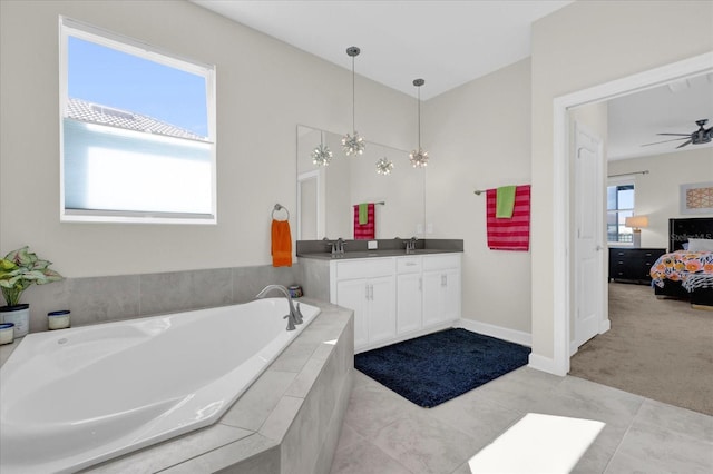 bathroom with a relaxing tiled tub, ceiling fan, vanity, and tile patterned flooring