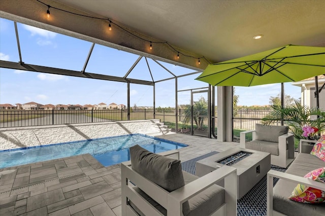 view of swimming pool with glass enclosure, a patio area, and an outdoor living space with a fire pit