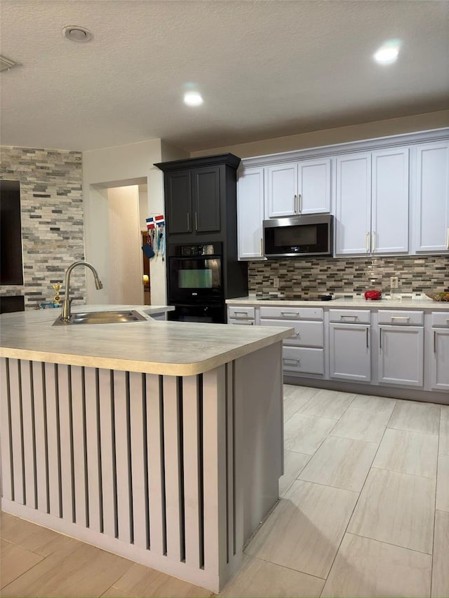 kitchen with sink, decorative backsplash, a textured ceiling, and black electric stovetop