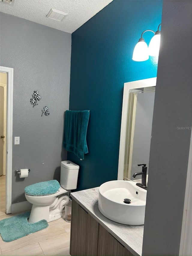 bathroom featuring vanity, hardwood / wood-style floors, a textured ceiling, and toilet