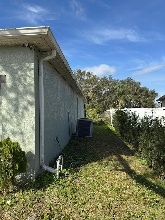 view of side of home featuring central AC and a yard