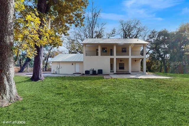 rear view of property with cooling unit, a balcony, a patio area, and a lawn