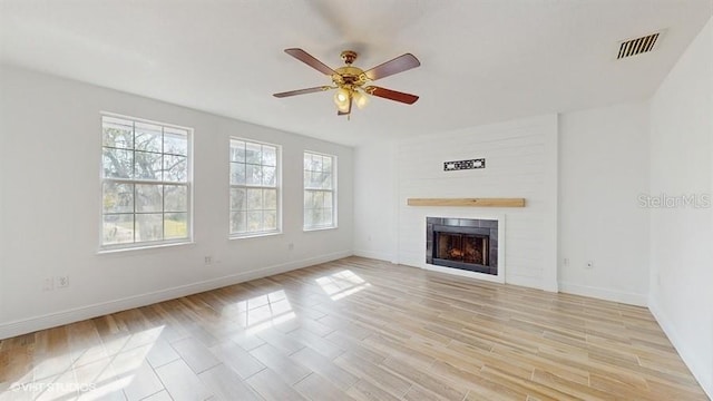 unfurnished living room with a large fireplace, ceiling fan, and light hardwood / wood-style flooring