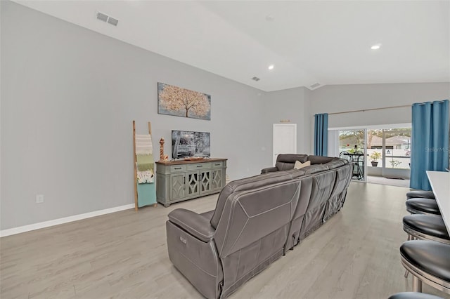 living room featuring lofted ceiling and light hardwood / wood-style flooring