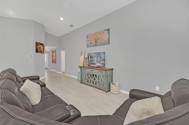 living room featuring high vaulted ceiling and light hardwood / wood-style flooring