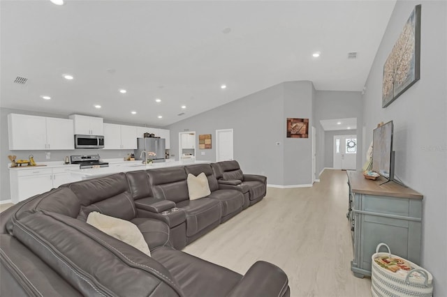 living room featuring light hardwood / wood-style flooring, sink, and vaulted ceiling