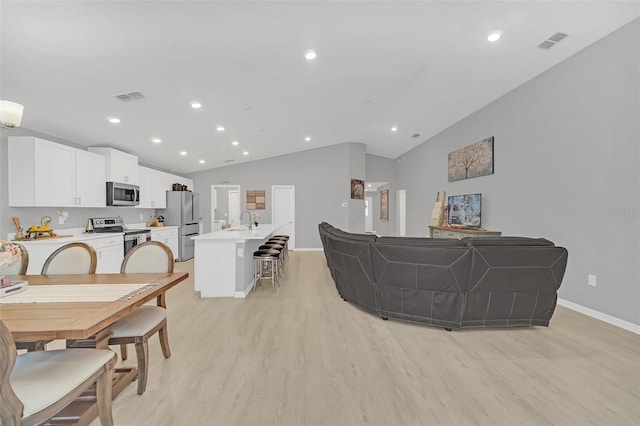 living room featuring sink, vaulted ceiling, and light wood-type flooring