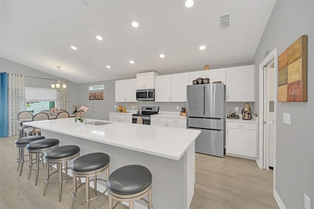 kitchen featuring a kitchen bar, sink, stainless steel appliances, a kitchen island with sink, and white cabinets