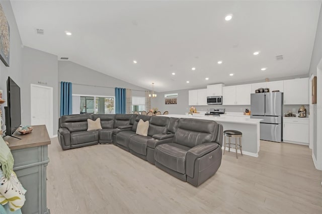 living room featuring light hardwood / wood-style flooring, a chandelier, and vaulted ceiling