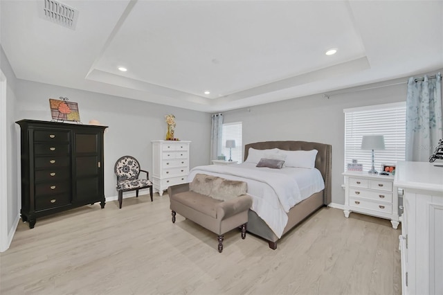 bedroom featuring a tray ceiling and light hardwood / wood-style flooring