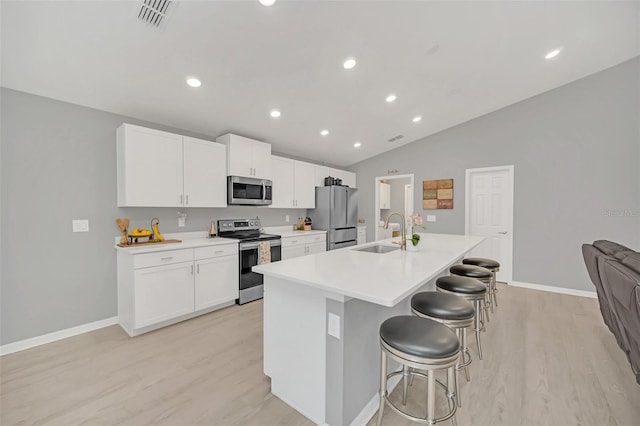 kitchen with appliances with stainless steel finishes, white cabinetry, an island with sink, sink, and a kitchen breakfast bar