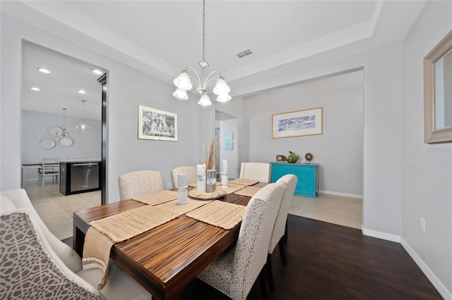 dining room with a notable chandelier, hardwood / wood-style flooring, and a raised ceiling