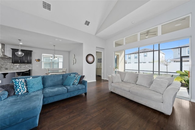 living room with a notable chandelier, high vaulted ceiling, and dark hardwood / wood-style floors